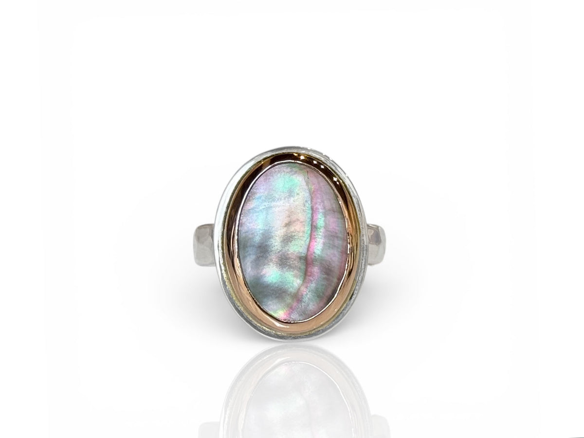 Oval black mother-of-pearl with iridescent tones in a rose gold bezel on a sterling silver ring