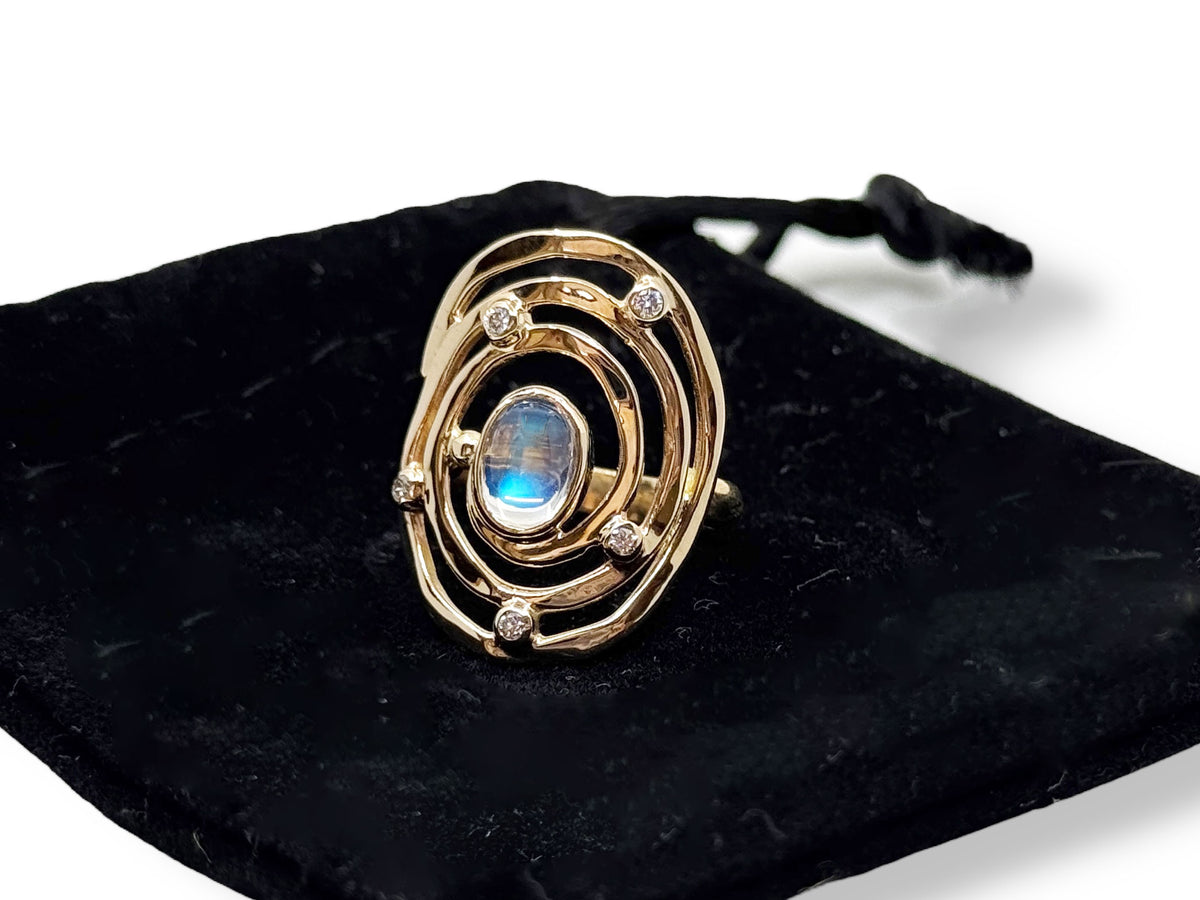 Gold Eye of the Storm moonstone and diamond ring on a black background