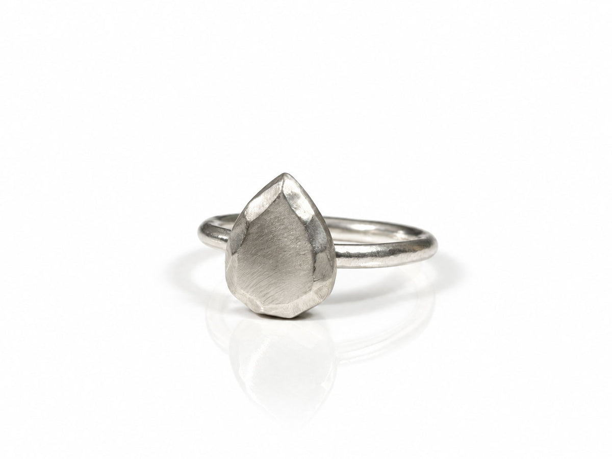Sterling silver solitaire-style ring sculpted like a pear-shaped faceted gem, with brushed facets on a smooth band