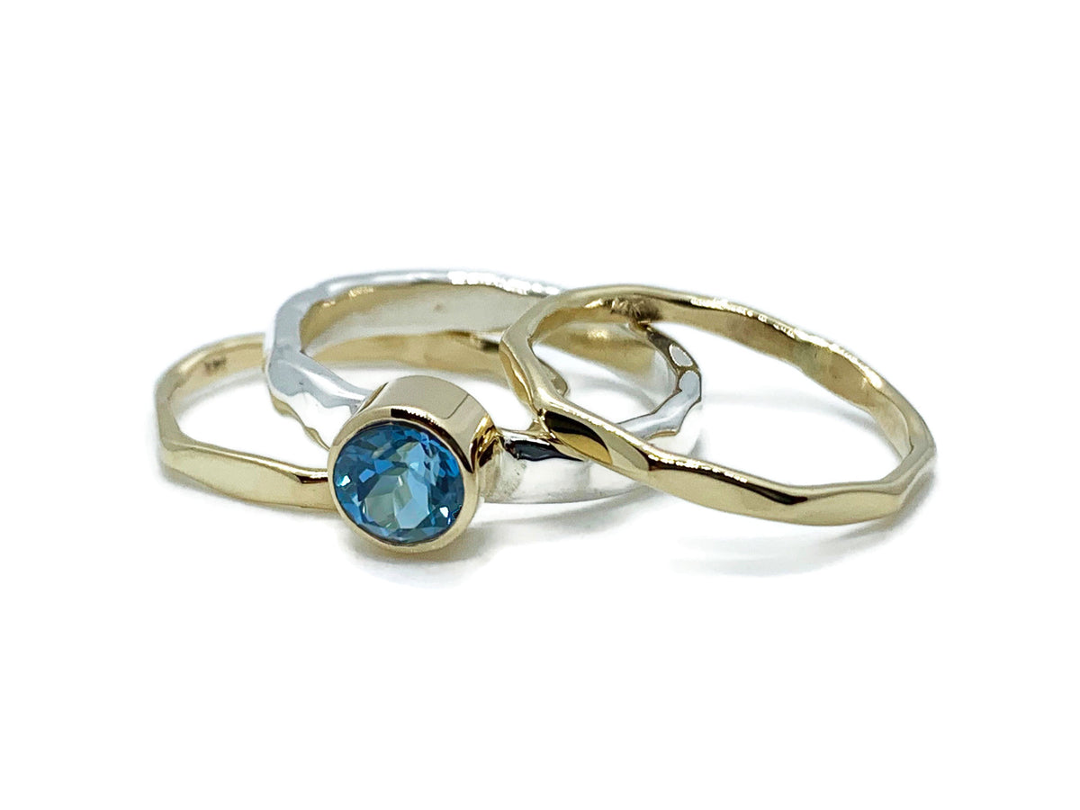 Bright Swiss blue topaz in a 14kt yellow gold bezel on a hammered sterling silver stack ring set