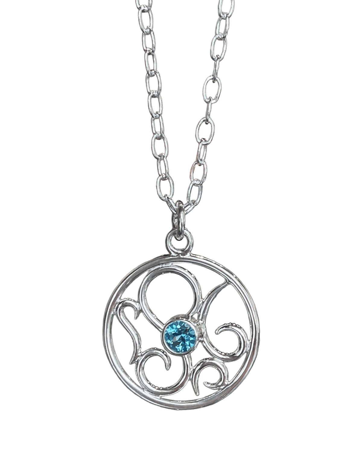 Round sterling silver medallion pendant with abstract octopus swirls around a faceted Swiss blue topaz