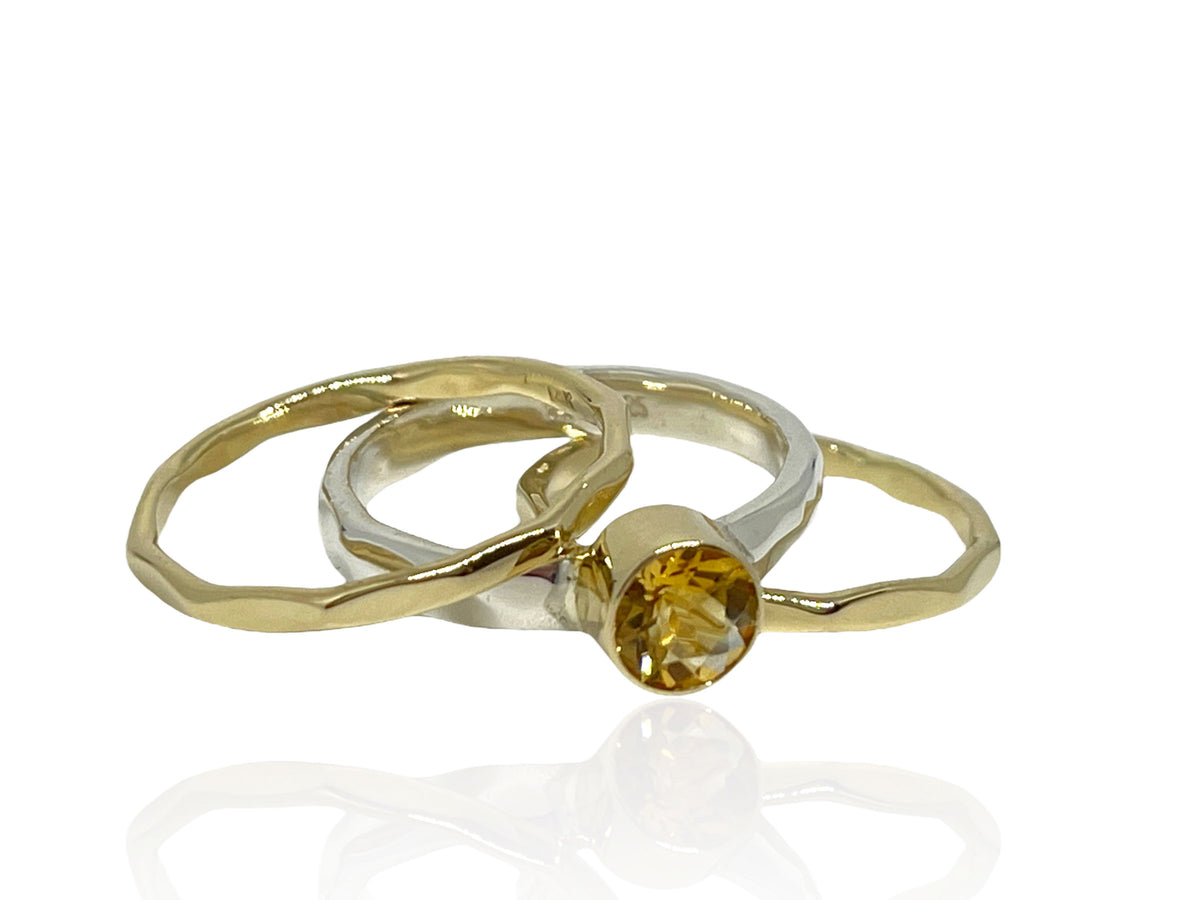 Faceted golden citrine in a 14kt yellow gold bezel on a hammered sterling silver stack ring set