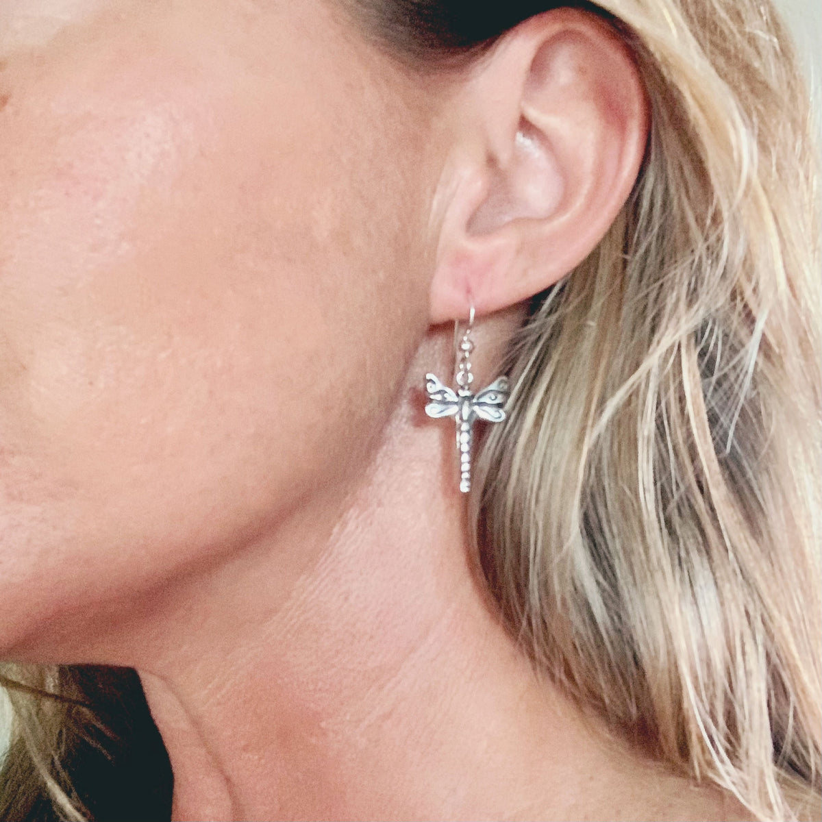 Alternate view of the pair of silver dragonfly earrings with swirl details, just under 1 inch tall