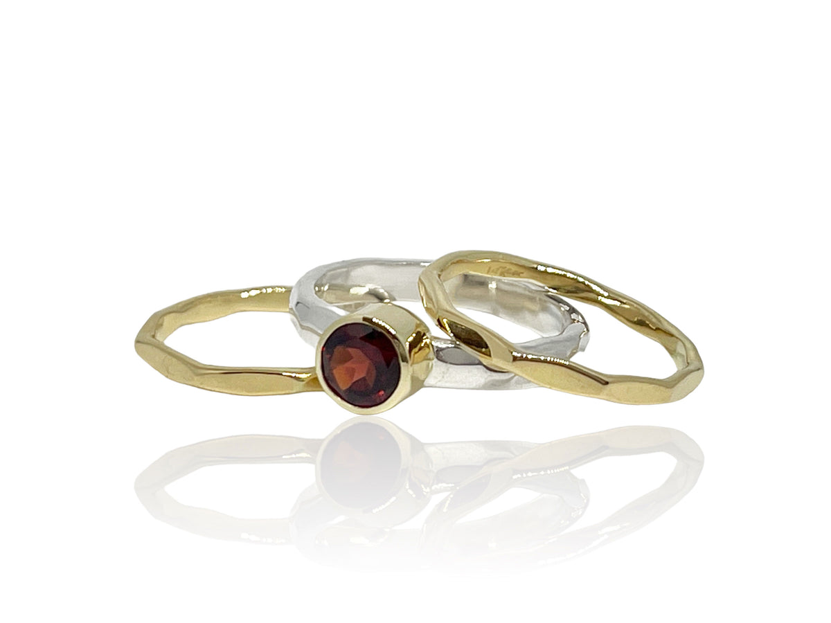 Deep crimson red garnet in a 14kt yellow gold bezel on a hammered sterling silver stack ring set