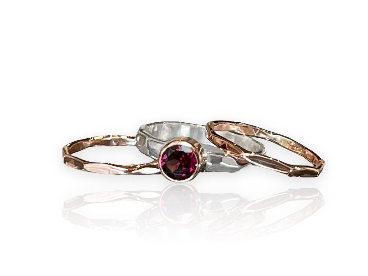 Raspberry-red rhodolite garnet in a 14kt rose gold bezel on a hammered sterling silver stack ring set