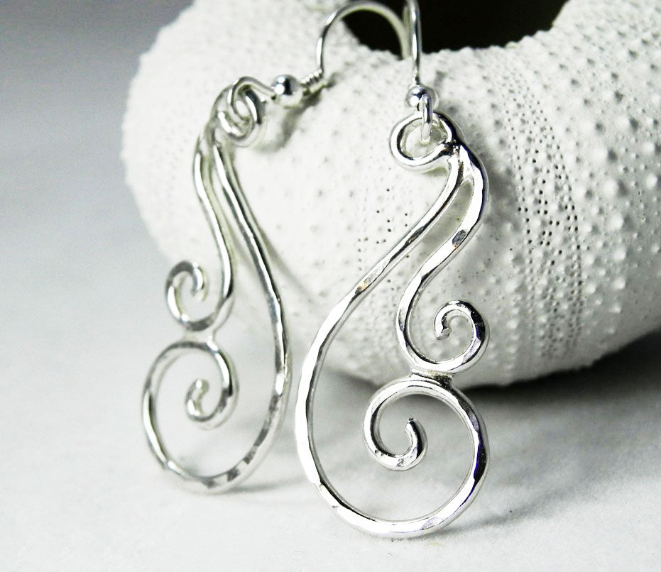 Alternate view of the hammered silver swirl dangle earrings showing their glistening texture