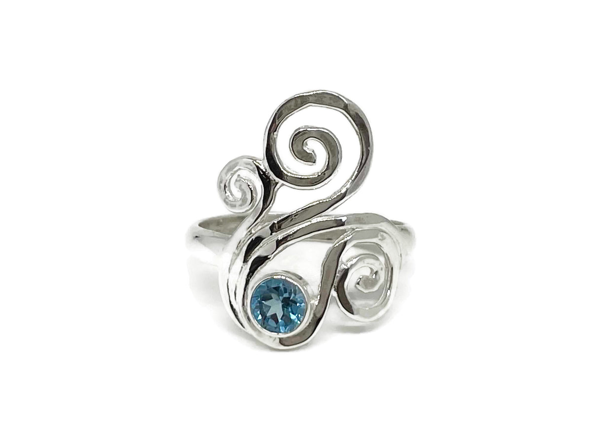 Asymmetrical sterling silver wave swirl ring with a bezel-set round blue topaz