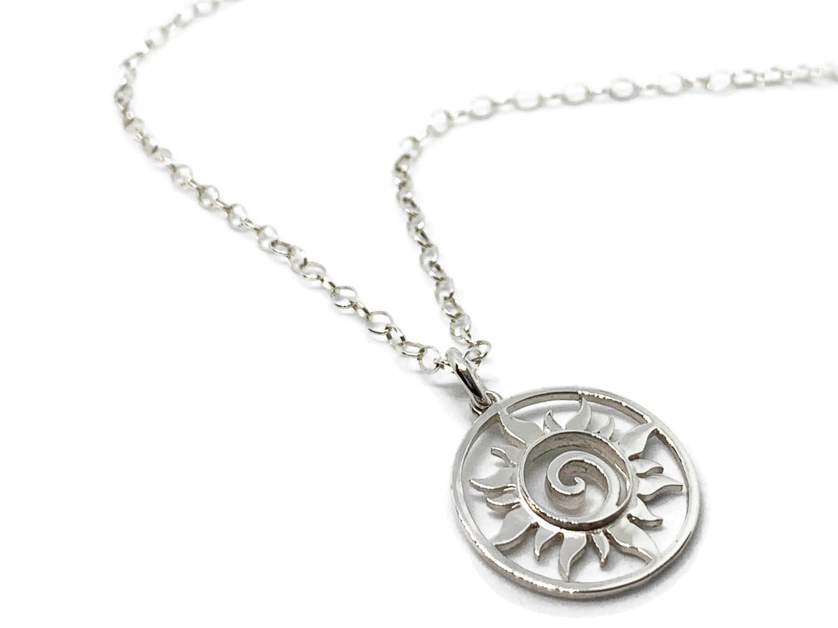 Close-up of the polished silver sun swirl medallion