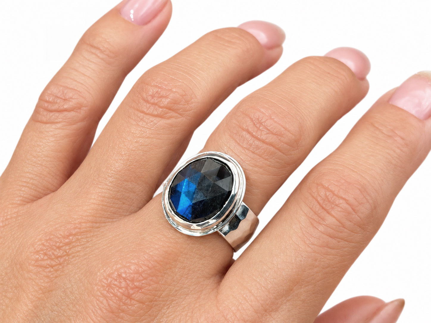Large faceted oval labradorite with a deep blue flash on an 8mm wide hammered sterling silver band